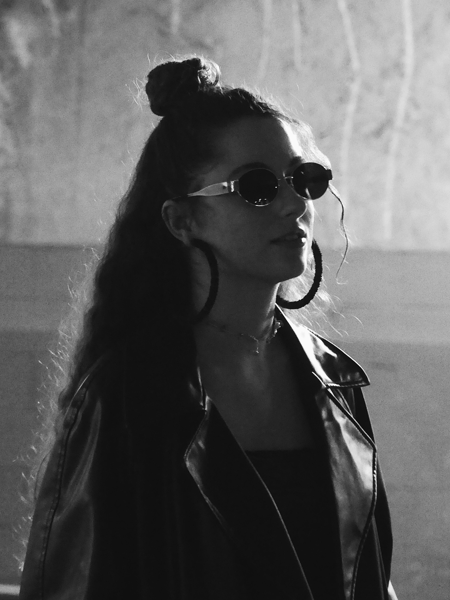 Black and white portrait of the same woman in sunglasses lit from behind.