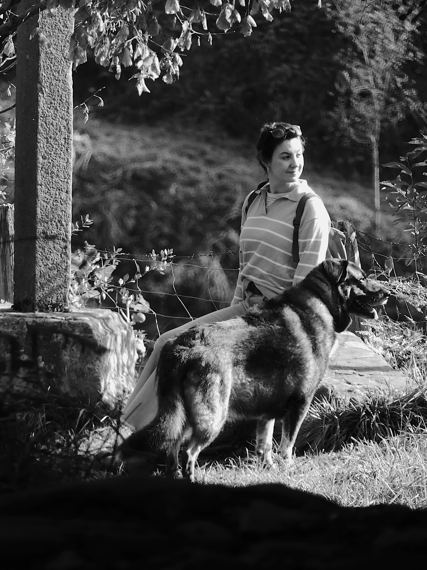 Black and white outdoor portrait of a woman seated beside a dog.