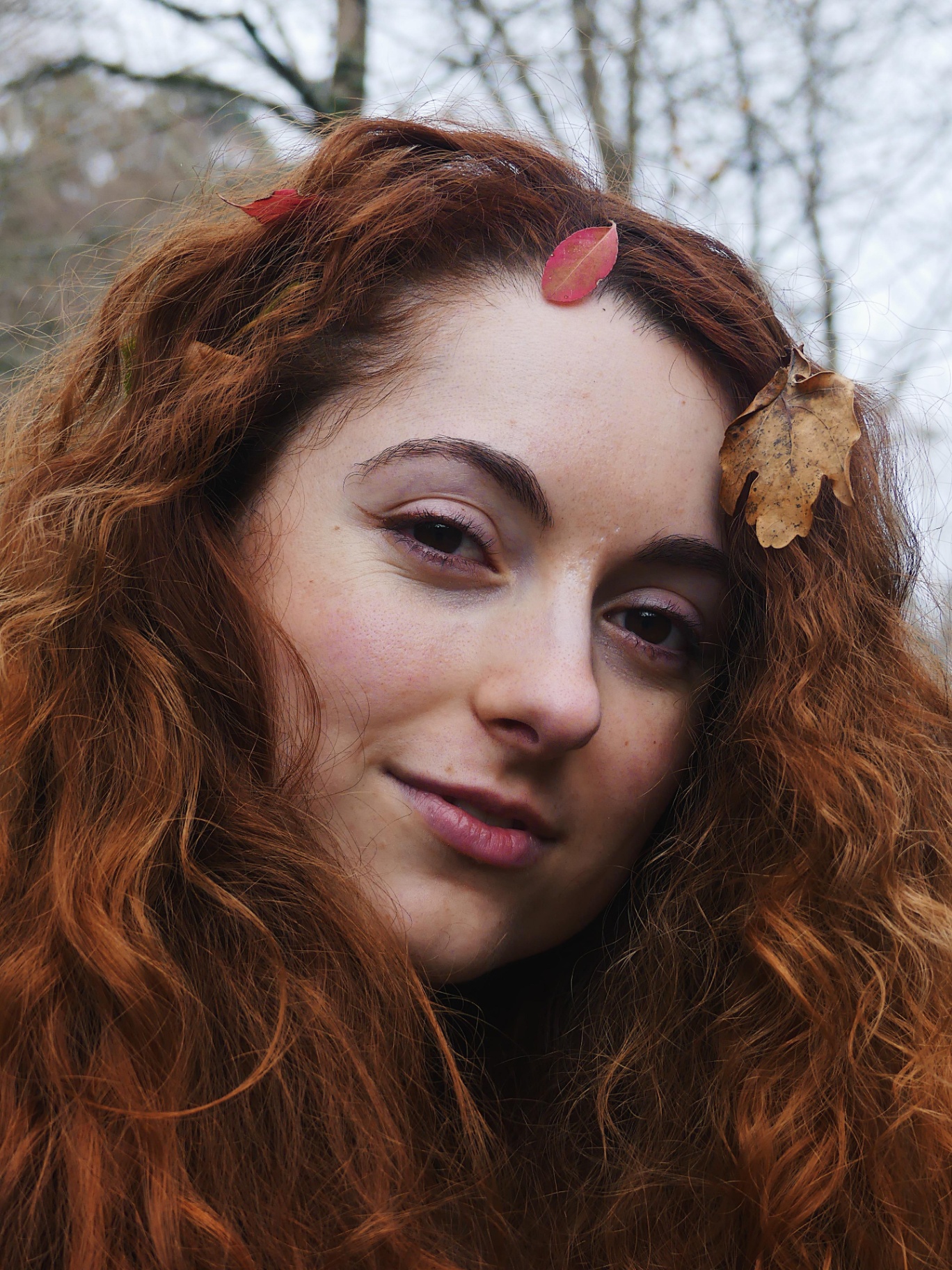 Portrait of a woman with red hair and autumn leaves.