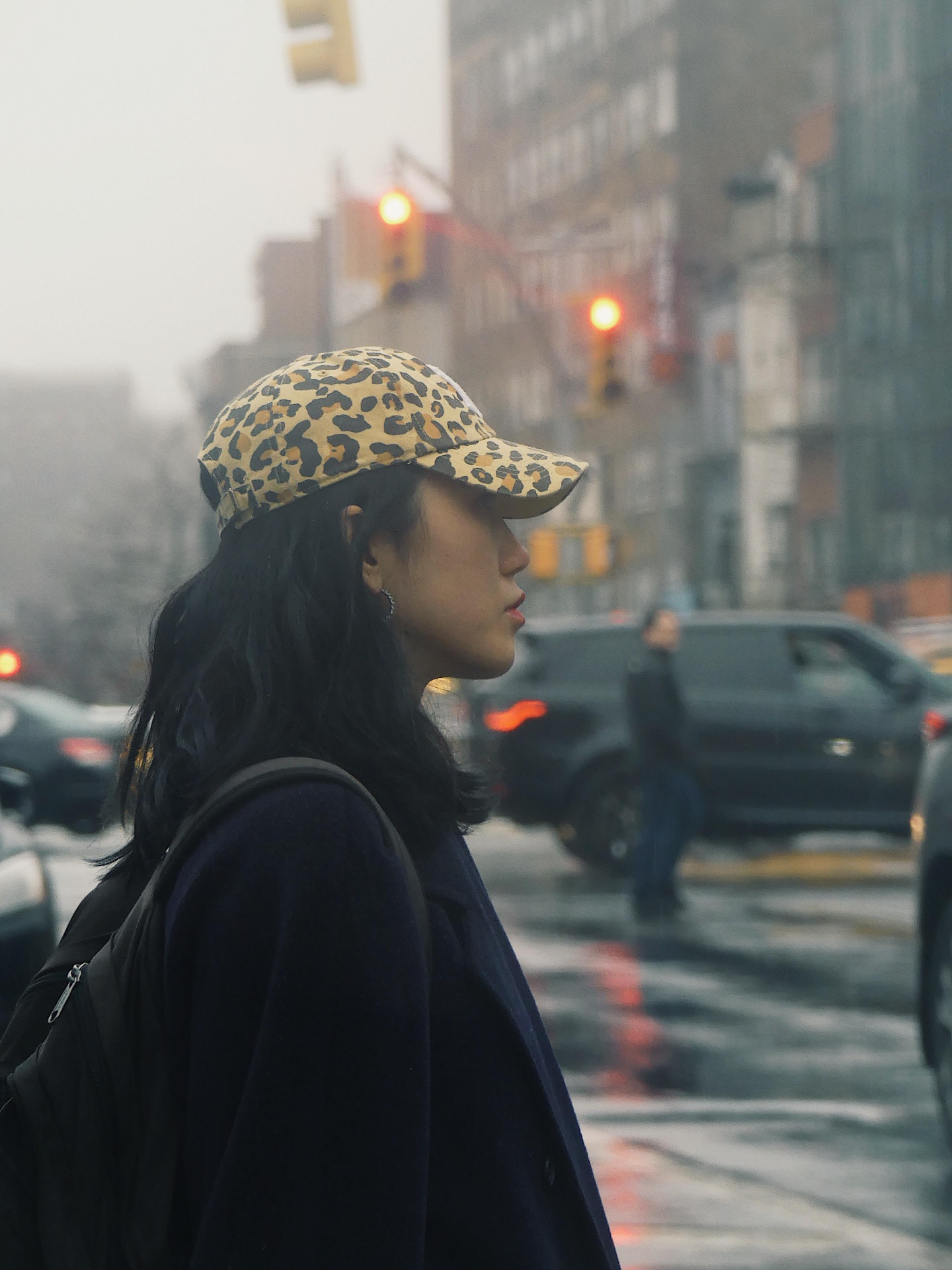 Profile of a woman in a leopard-print cap on a rainy New York street.