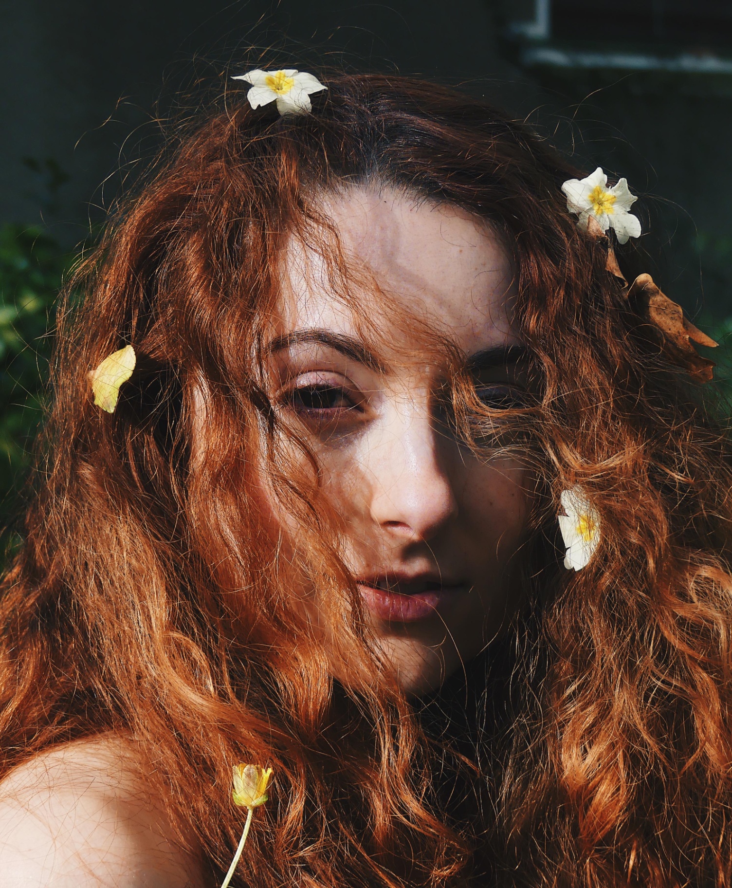 Close-up portrait of a red-haired woman with white flowers in her hair.
